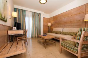 厄尔梅达诺Kn Hotel Arenas del Mar Adults Only的一间配有沙发、一张桌子和一台电视的酒店客房