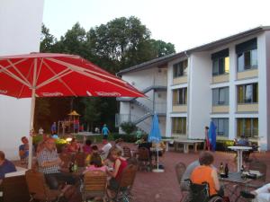慕尼黑慕尼黑公园青年旅舍的一群人坐在红伞下的椅子上
