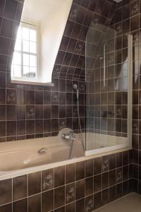 布鲁日勃艮第公爵奥克斯酒店的一间带浴缸和淋浴的浴室以及窗户。