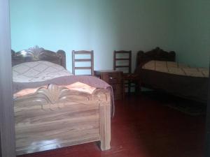 MazeriMila Guest House的一间卧室设有两张床和几把木椅