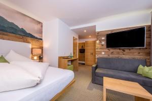 弗林肯贝格M&M山区度假酒店的一间卧室配有一张床、一张沙发和一台电视。