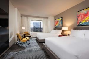 布卢明顿Hyatt Regency Bloomington - Minneapolis的酒店客房带两张床和一张桌子以及椅子。