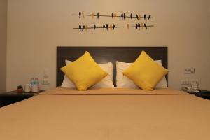 宿务马布洛罗伊尔酒店的一张床上有黄色枕头,墙上有鸟儿