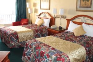 代托纳海滩格兰德普利克斯海滨汽车旅馆的酒店客房,设有两张床和一张红色椅子