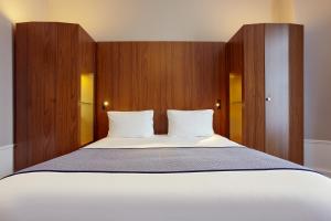 巴黎Holiday Inn Paris - Gare de Lyon Bastille, an IHG Hotel的卧室配有一张白色大床和木镶板