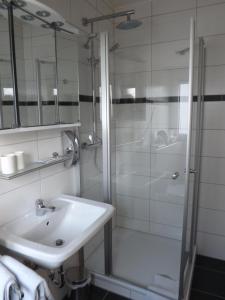 摩泽尔河畔的泽尔B&B Pension Winzerhaus Zell-Mosel的带淋浴和盥洗盆的白色浴室