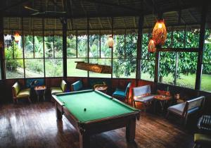 马尔多纳多港Corto Maltes Amazonia Lodge的客房设有台球桌、椅子和窗户。