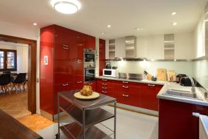 凯泽贝尔KAYSERSBERG city center - House "AUX 7 FORGERONS" -的厨房配有红色橱柜和一张桌子,上面有盘子