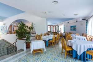 博尼法蒂Hotel Club Residence Martinica的餐厅设有白色的桌子和黄色的椅子