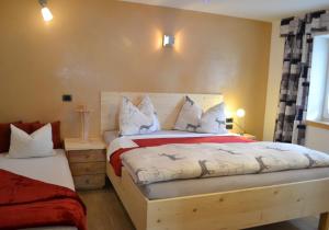瓦尔道拉Ferienwohnung Pramstaller的一间卧室配有一张铺有白色和红色床单的床