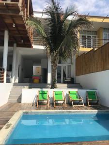 维加伊托Casa de playa Vichayito Relax的一座房子旁的游泳池,里面摆放着椅子和棕榈树