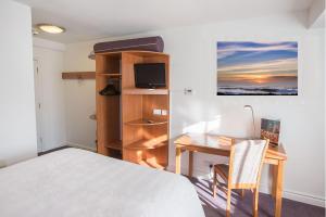 索利赫尔Redwings Lodge Solihull的一间卧室配有一张床、一张桌子、一张床和一张桌子及椅子