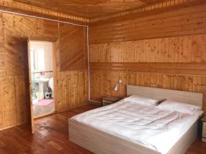 米库利钦Котедж "Relax"的卧室配有木墙内的一张床