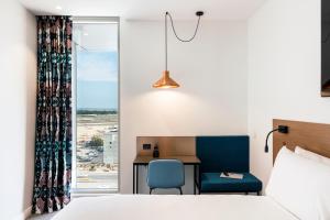 悉尼Citadines Connect Sydney Airport的酒店客房,配有一张床、一张桌子和椅子