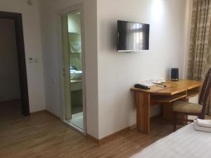 布哈拉利亚比之家酒店的酒店客房设有一张桌子和一台墙上的电视