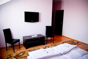 NyírpazonyPazonyi Fogadó és Étterem的一间卧室配有一张床、两把椅子和一台电视