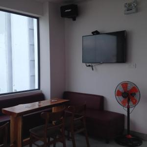 芽庄芽庄邦迪背包客旅舍的一间设有桌子和墙上电视的房间