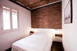巴塞罗那Barceloneta Suites Apartments Beach的卧室配有白色的床和砖墙