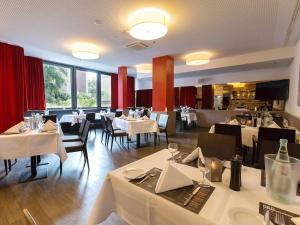 汉诺威汉诺威多梅洛酒店的餐厅设有白色的桌椅和窗户。