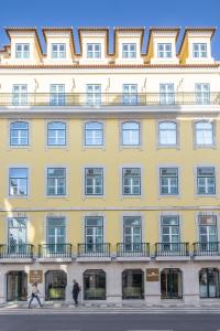 里斯本Hotel MeraPrime Gold Lisboa的一座黄色的大建筑,前面的人在步行