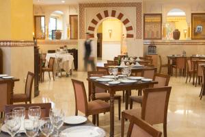 科尔多瓦欧洲之星迈蒙尼德酒店的一间设有桌椅的餐厅,以及一位背景人士