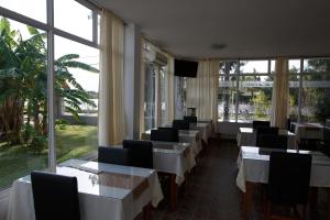 Gualeguaychú彼德拉斯德尔科斯塔山林小屋的餐厅设有白色的桌椅和窗户。