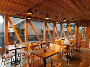 纳塔列斯港Hostal Boutique Factoria Patagonia的餐厅设有木桌、椅子和窗户。