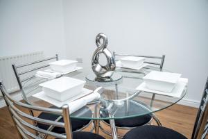 北安普敦Luxuriant Apartments的玻璃桌子和椅子,上面有白色的菜肴