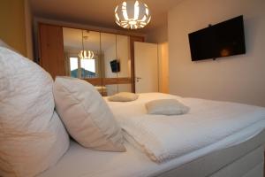 库克斯港Wohnen am Yachthafen W45的卧室配有带枕头的白色床和电视。