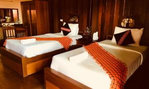 Ban Khun Yuam米特胡恩佑姆酒店的一间卧室配有3张床,提供橙色和白色床单