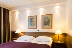 伊纳利因阿里酒店的酒店客房,配有一张床,墙上挂有两张照片