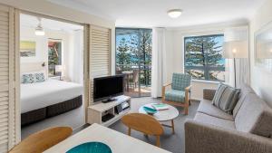 黄金海岸Oaks Gold Coast Calypso Plaza Suites的客厅配有床、沙发和电视。