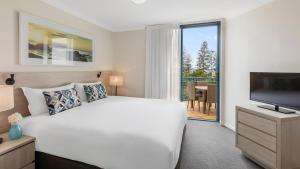 黄金海岸Oaks Gold Coast Calypso Plaza Suites的卧室配有一张白色大床和电视。