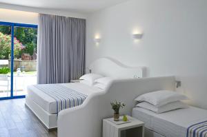 佩基罗德林迪亚塔拉萨酒店的一间白色卧室,配有两张床和一个阳台
