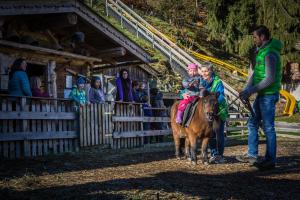 卡顿巴赫Alpin Family Resort Seetal的和孩子骑小马的男人和孩子