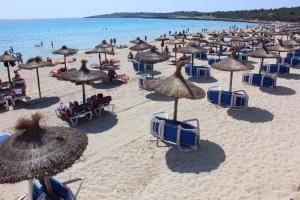 卡拉米洛Sol y Luna Cala Millor的海滩上有许多椅子和遮阳伞,还有大海