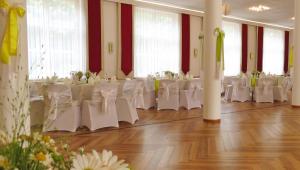 奥拉宁鲍姆金色法桑酒店的宴会厅配有白色的桌子和白色的椅子