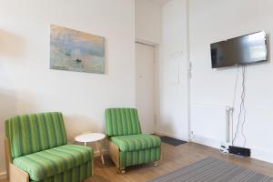 柏林Stylish & Cosy Apartment in Berlin, WiFi的客厅配有两把椅子和电视