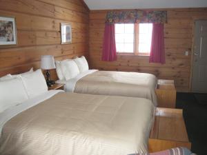 北湾日落酒店的配有木墙和窗户的客房内的两张床
