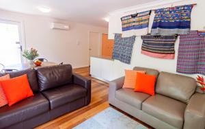 堪培拉万伊凯德公寓酒店的客厅配有两张真皮沙发和橙色枕头