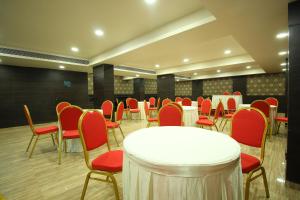 苏拉特Central Beacon Hotel的一间会议室,配有白色的桌子和红色的椅子