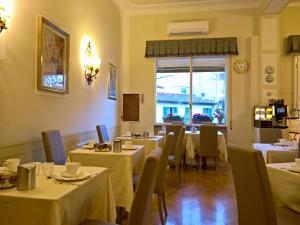 佛罗伦萨大卫酒店的餐厅设有白色的桌椅和窗户。