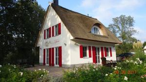 格洛韦Ferienhaus Lucia的一间白色的小房子,设有红色百叶窗