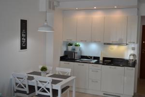 斯维诺乌伊希切Apartament Aleksandra的厨房配有白色橱柜和桌椅