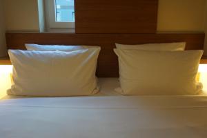 柏林柏林哈克市场便捷酒店的一张带两个白色枕头和床头板的床