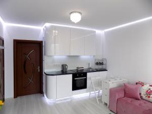 瓦尔纳Apartment Silvi的一间小厨房,配有白色的橱柜和粉红色的沙发