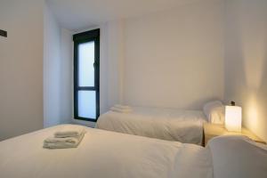 隆达洛杉矶雷梅迪奥斯刘易斯和彼得公寓的白色的客房设有两张床和窗户。