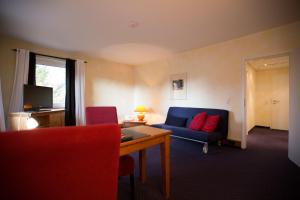 费尔巴赫布克勒酒店的客厅配有蓝色的沙发和红色的椅子