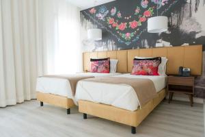 纳扎雷魔术酒店的卧室内的两张床,墙上挂着鲜花