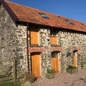 南莫尔顿East Trayne Holiday Cottages的石头建筑,设有木门和红色屋顶